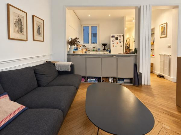 Interior of a Haussmannian apartment in Paris 9, with a bright living room and a kitchen area.