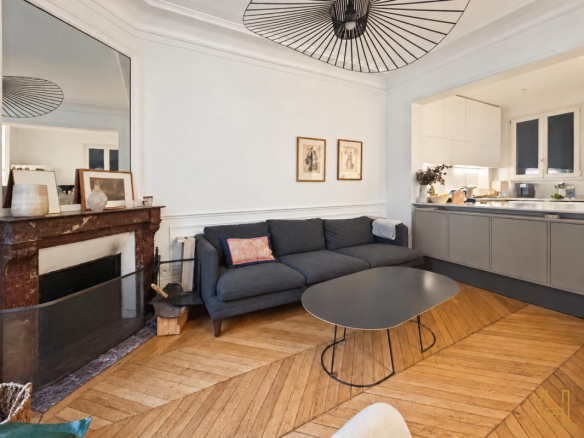 Living room of a Haussmannian apartment in Paris 9th arrondissement, with herringbone parquet flooring and a marble fireplace.