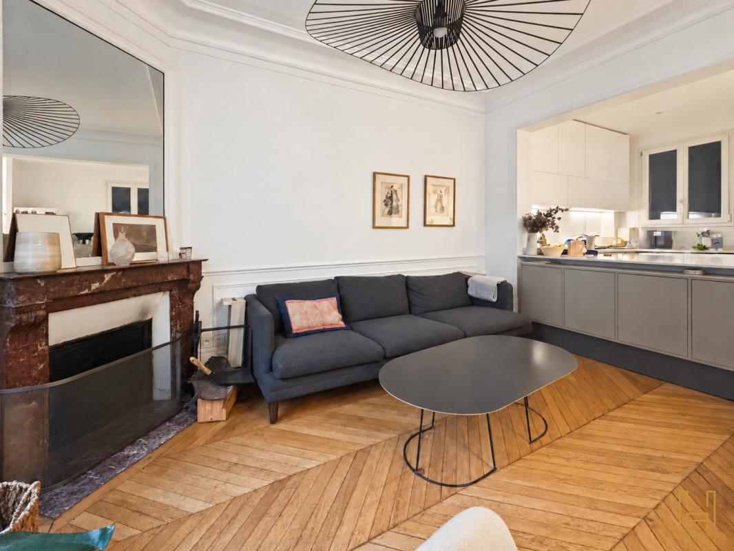 Living room of a Haussmannian apartment in the 9th arrondissement of Paris Living room of a Haussmannian apartment in Paris 9th arrondissement, with herringbone parquet flooring and a marble fireplace.