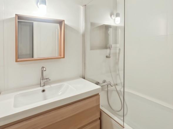 Modern bathroom with bathtub, sink and wooden mirror.