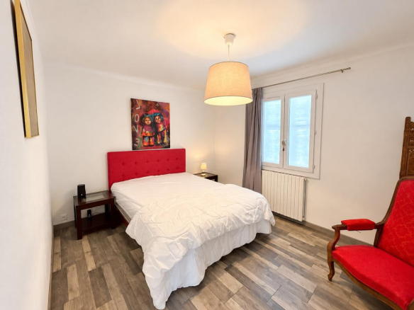 Chambre d'une propriété avec lit double et fauteuil rouge, située à La Gaude.