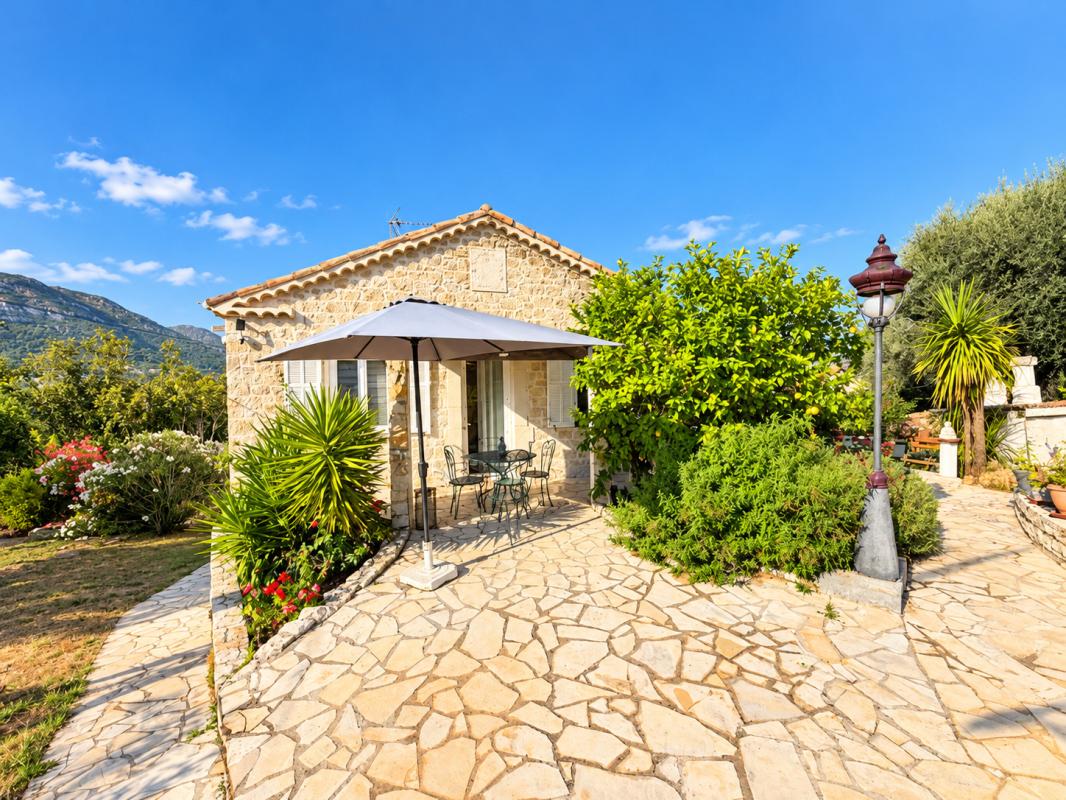 Propriété avec piscine et vue sur les Baous Maison en pierre avec terrasse et parasol, entourée de verdure, vue sur les Baous à La Gaude.
