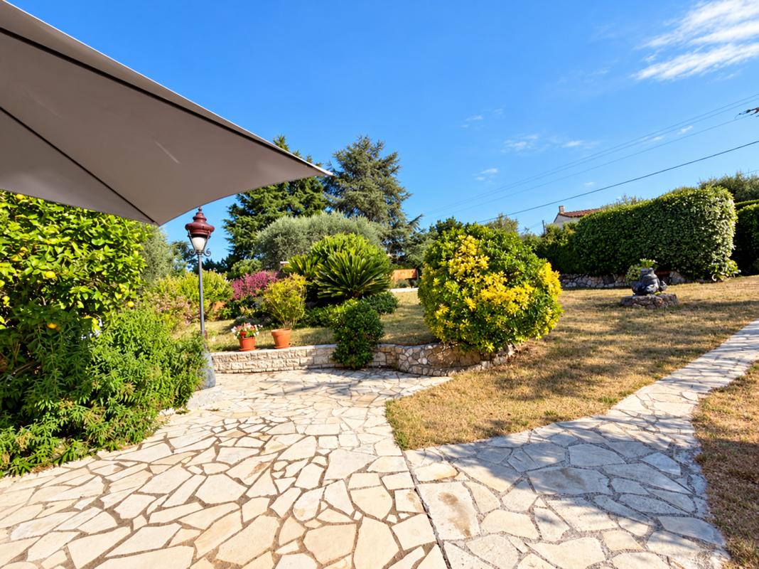 Propriété avec jardin et piscine à La Gaude Jardin arboré avec allée en pierre et parasol, vue dégagée sur un espace vert.
