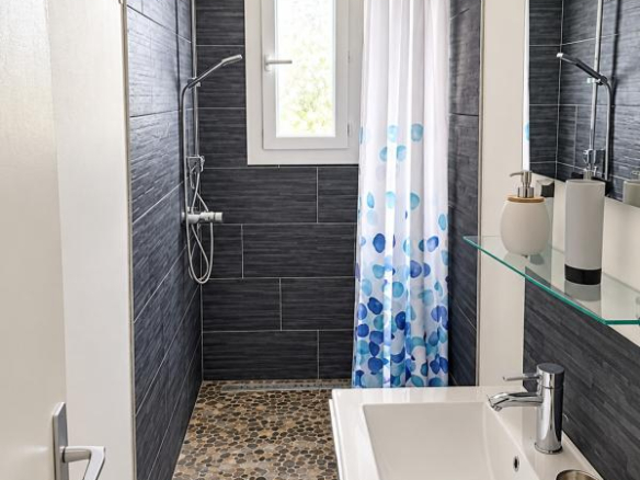 Salle de bain moderne avec douche à l'italienne et lavabo, décorée de carrelage gris et mosaïque.