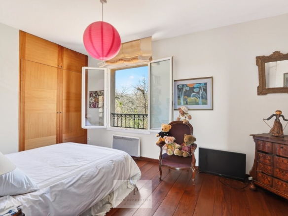 Chambre d'une villa avec fenêtre ouverte et meubles en bois, décorée de peluches.