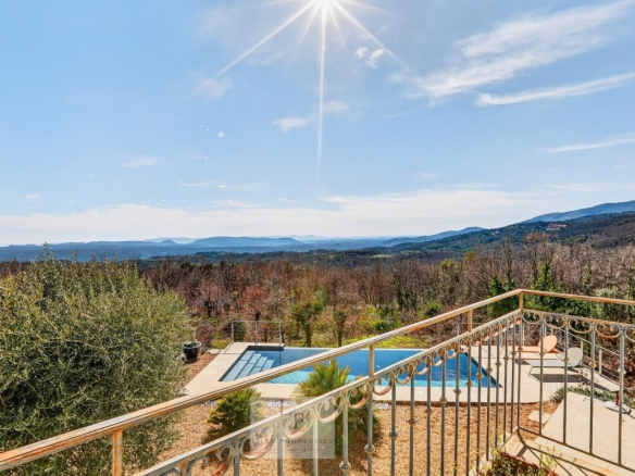 Vue panoramique depuis une villa surplombant un paysage provençal avec piscine.