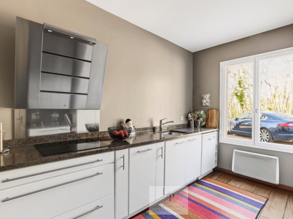 Cuisine moderne avec plans de travail en granit et fenêtre donnant sur l'extérieur.