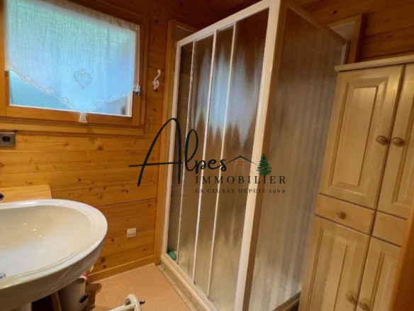 Salle de bain dans un chalet en bois avec douche et lavabo