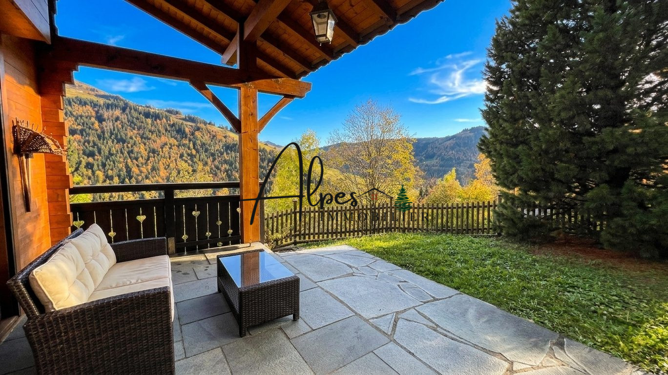 Chalet d’exception à La Clusaz Terrasse d'un chalet avec vue sur les montagnes à La Clusaz, entourée d'arbres.