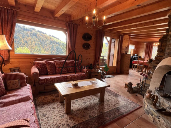 Intérieur d'un chalet en bois avec salon confortable et vue sur la montagne.