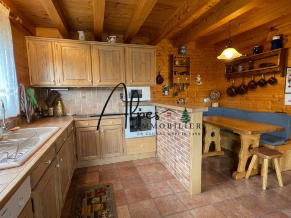 Cuisine en bois d'un chalet avec table et banc, vue sur le plan de travail en carrelage.