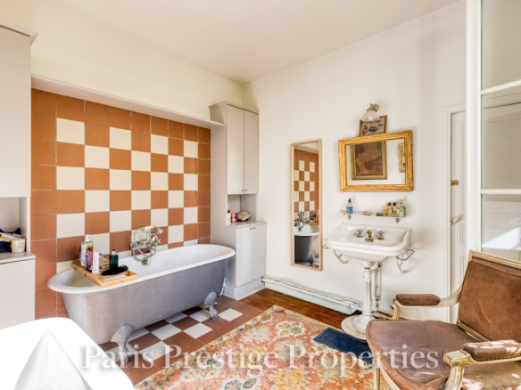 Salle de bain d'un ancien atelier d'artiste à Paris, avec baignoire, lavabo et miroir.