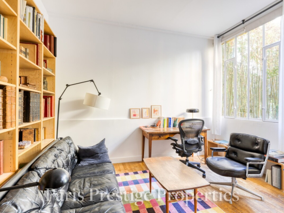 Intérieur d'un ancien atelier d'artiste avec un canapé, une bibliothèque et un bureau.
