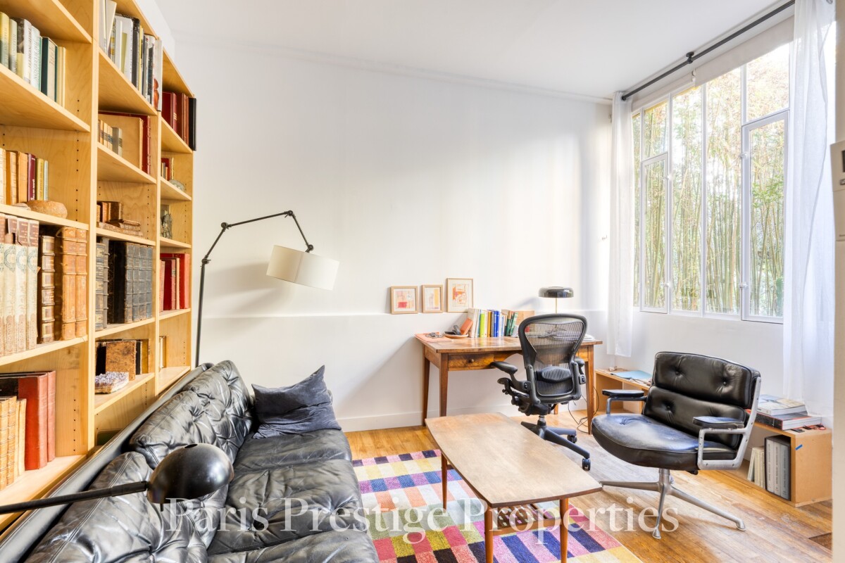 Intérieur d’un atelier d’artiste à Paris Intérieur d'un ancien atelier d'artiste avec un canapé, une bibliothèque et un bureau.