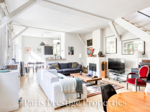 Intérieur d'un ancien atelier d'artiste à Paris, avec un salon lumineux et un espace de vie chaleureux.
