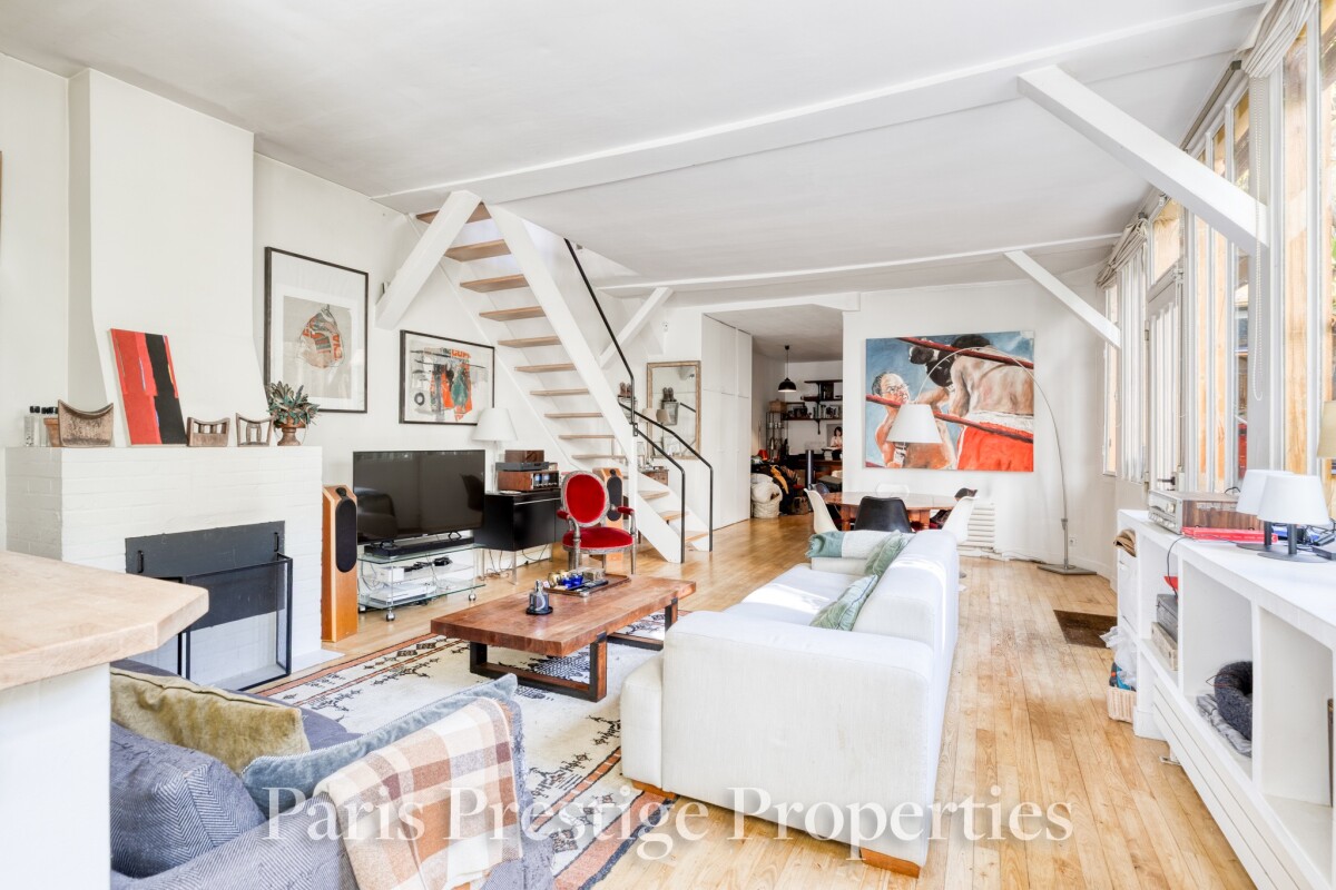 Ancien atelier d’artiste à Paris Intérieur d'un ancien atelier d'artiste à Paris, avec un salon lumineux et un escalier en bois.