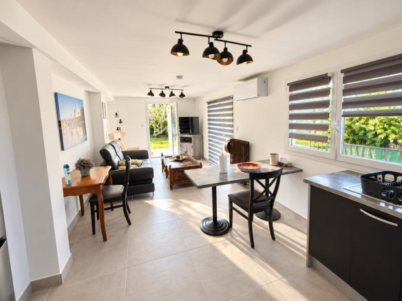 Intérieur d'une propriété avec salon, table à manger et cuisine ouverte, baies vitrées sur l'extérieur.