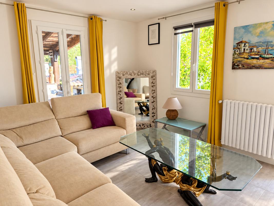 Salon moderne avec vue sur l’extérieur Intérieur d'un salon moderne avec canapé beige, table en verre et décoration artistique.