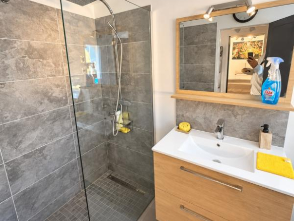 Salle de bain moderne avec douche en verre et meuble en bois.