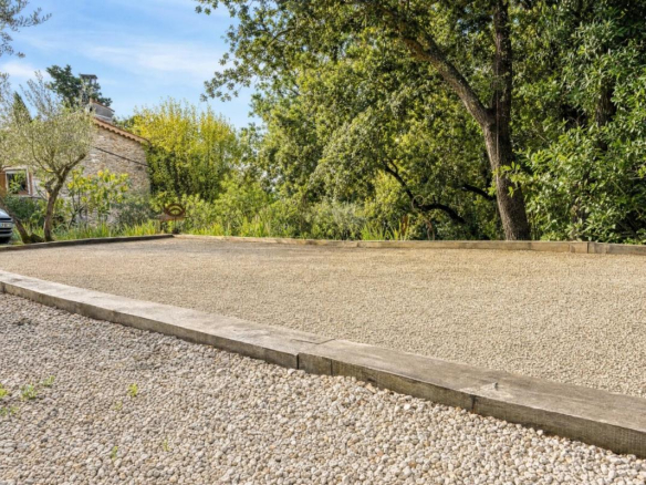 Terrasse en gravier entourée de verdure près d'une bergerie en pierre à Lorgues.