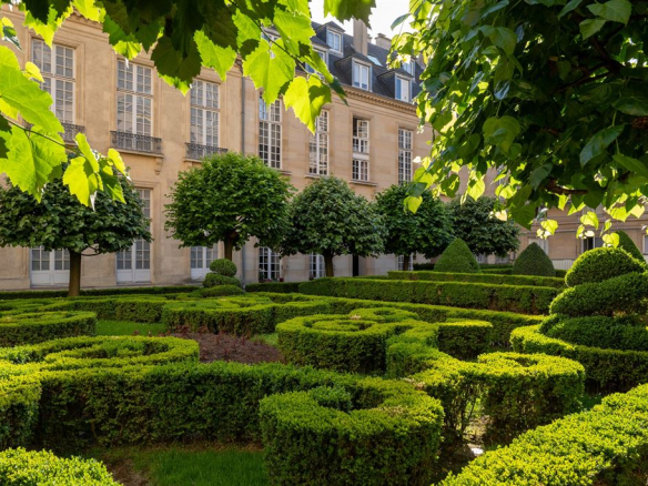 Well-maintained gardens with hedges and trees in a residence in the 3rd arrondissement of Paris.