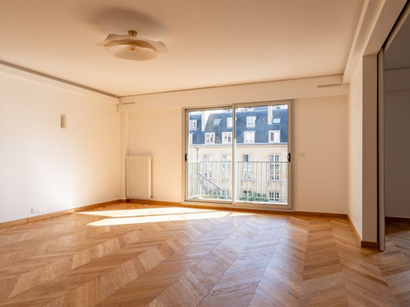 Interior of a renovated apartment with parquet flooring, natural light and views of gardens in Paris 3rd arrondissement.