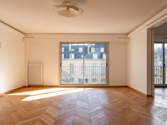Interior of a renovated apartment with parquet flooring and windows opening onto a balcony