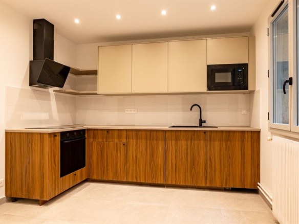 Modern kitchen with wooden furniture and integrated appliances in a renovated apartment.