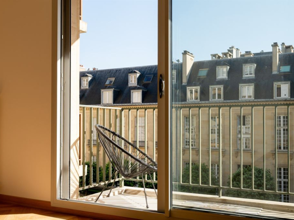 View from a balcony with a chair overlooking gardens in a renovated apartment in Paris 3rd arrondissement.