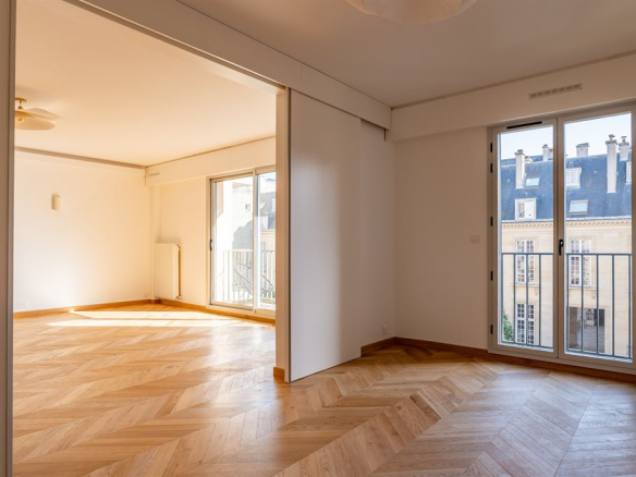 Interior of a renovated apartment with parquet flooring, windows and natural light, located in the Marais district of Paris.