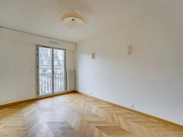 Interior of a renovated apartment with parquet flooring and access to a balcony, located in the Marais district of Paris.