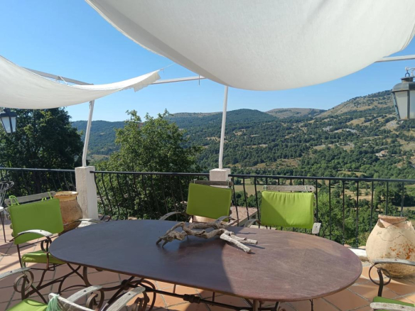 Terrasse d'une ancienne auberge à Coursegoules avec vue sur les collines environnantes.