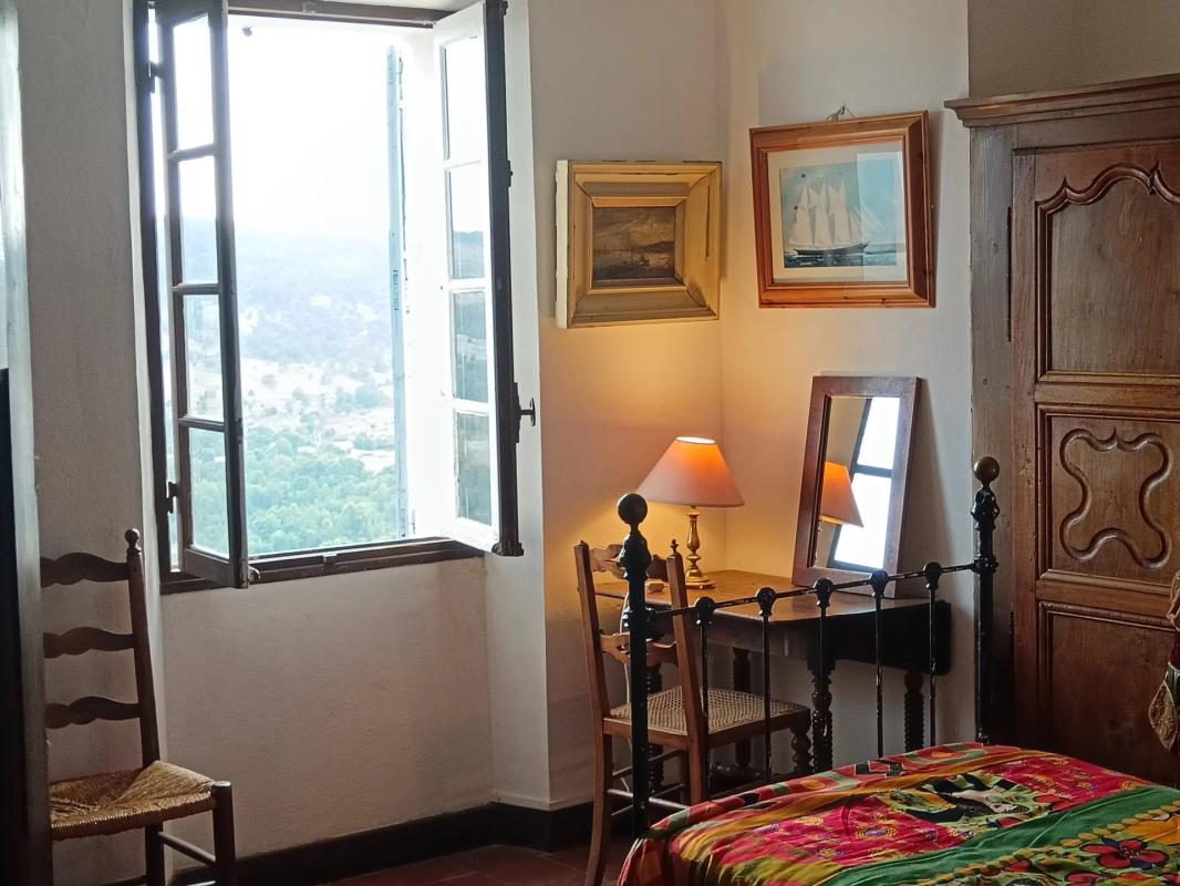 Chambre de l’ancienne auberge à Coursegoules Chambre d'une ancienne auberge à Coursegoules avec fenêtre ouverte et décor chaleureux.