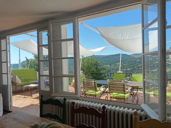 Vue intérieure d'une ancienne auberge avec terrasse et panorama sur la nature à Coursegoules.