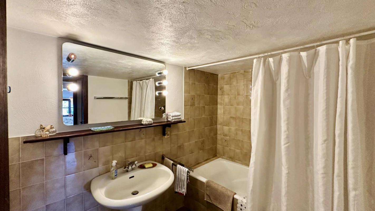 Salle de bain de la villa au Tignet Salle de bain avec baignoire, lavabo et miroir, murs carrelés en beige.