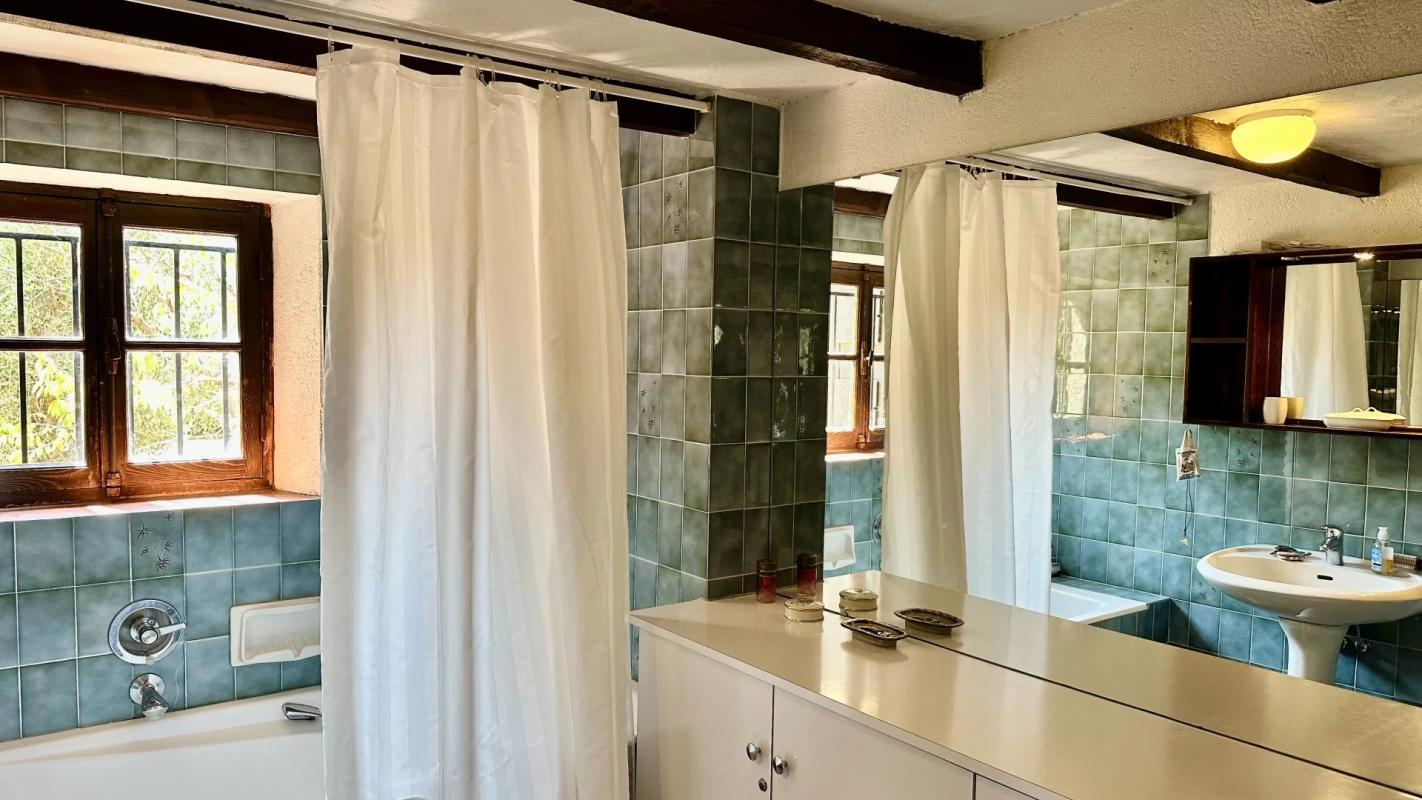 Salle de bain de la villa au Tignet Salle de bain d'une villa avec carrelage bleu et miroir, fenêtres en bois.