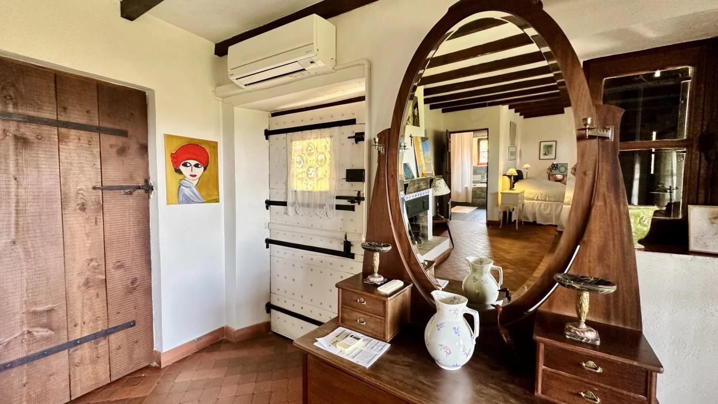 Intérieur d’une villa de charme Intérieur d'une villa avec miroir ovale, meuble en bois et décoration artistique.