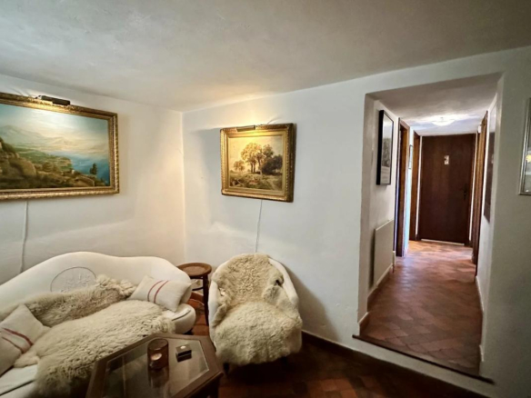 Intérieur d'une villa avec un salon confortable, des tableaux accrochés au mur et un couloir menant à d'autres pièces.