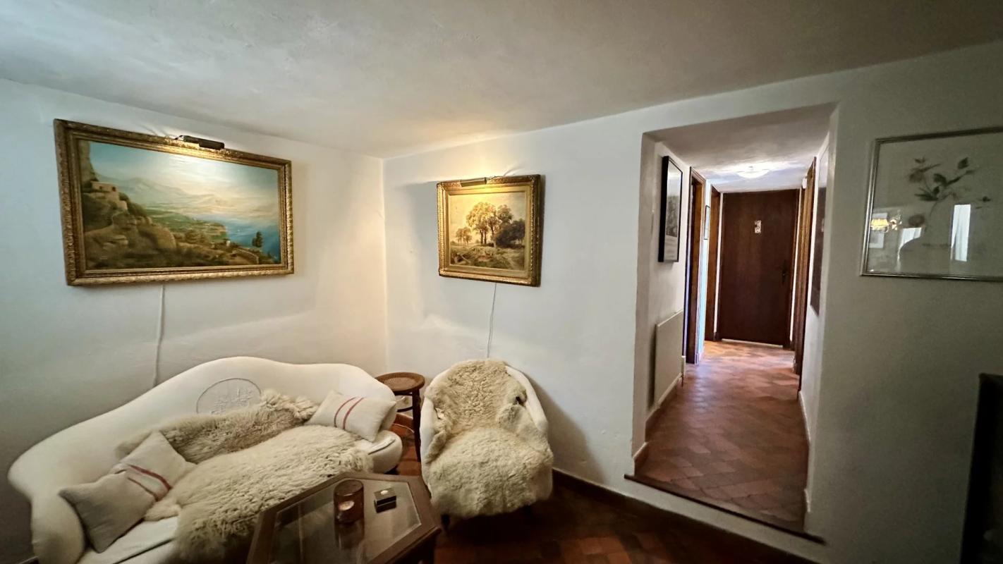 Intérieur d’une villa de charme Intérieur d'une villa avec un salon confortable, des tableaux accrochés au mur et un couloir menant à d'autres pièces.