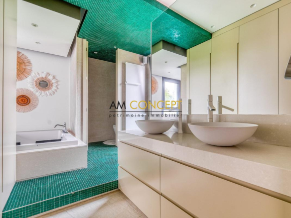Salle de bain moderne avec baignoire et vasques, carrelage vert et décorations murales.