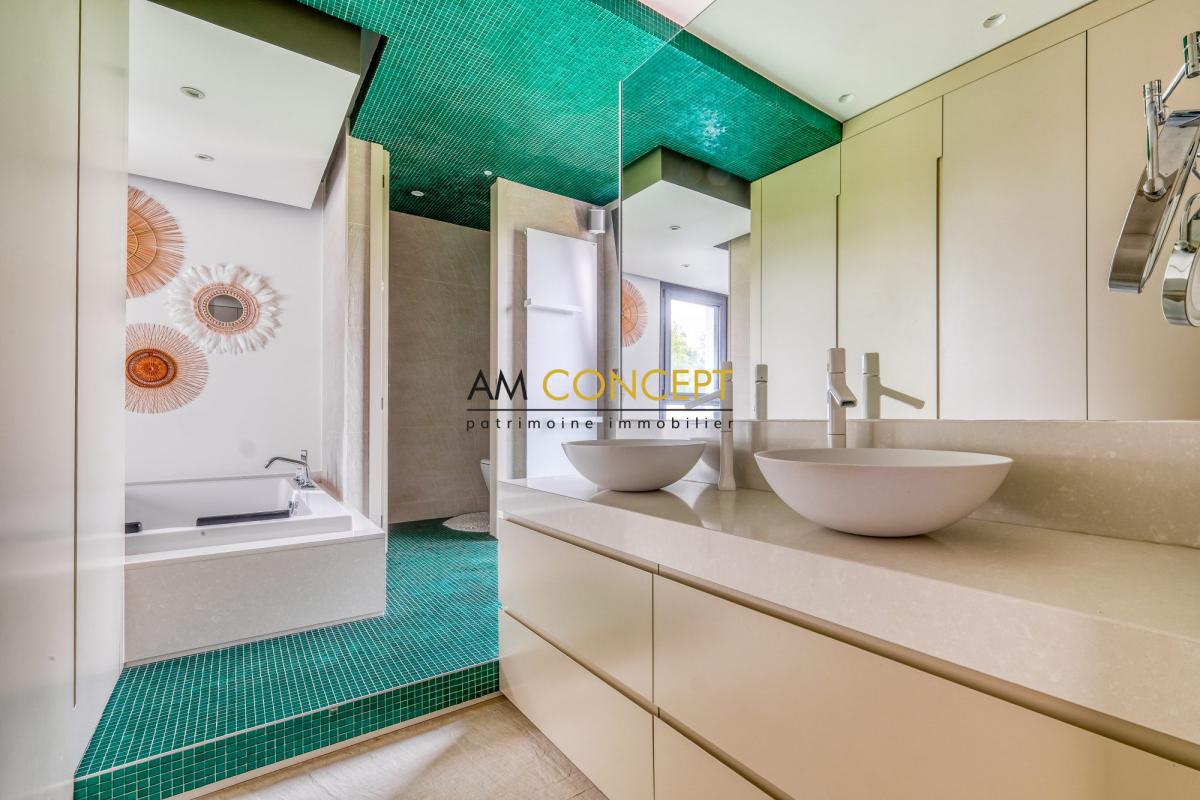 Salle de bain contemporaine Salle de bain moderne avec baignoire et vasques, carrelage vert et décorations murales.