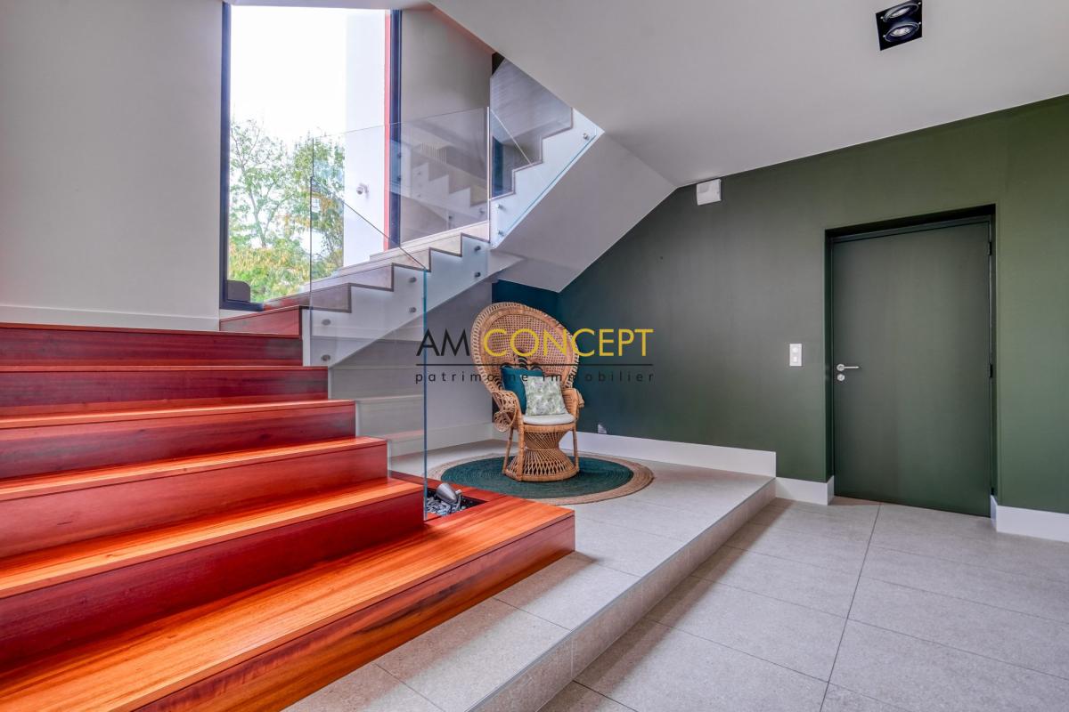 Intérieur moderne d’une maison d’architecte Intérieur d'une maison d'architecte avec un escalier en bois et un coin salon confortable.