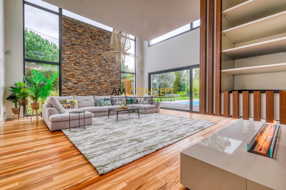 Salon d’une maison d’architecte à Chessy Intérieur d'une maison d'architecte avec un salon moderne, grandes fenêtres et cheminée.