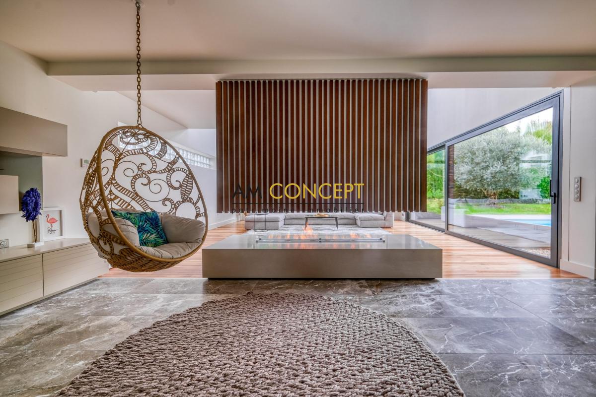 Intérieur d’une maison contemporaine à Chessy Intérieur d'une maison d'architecte avec un salon moderne et une chaise suspendue.