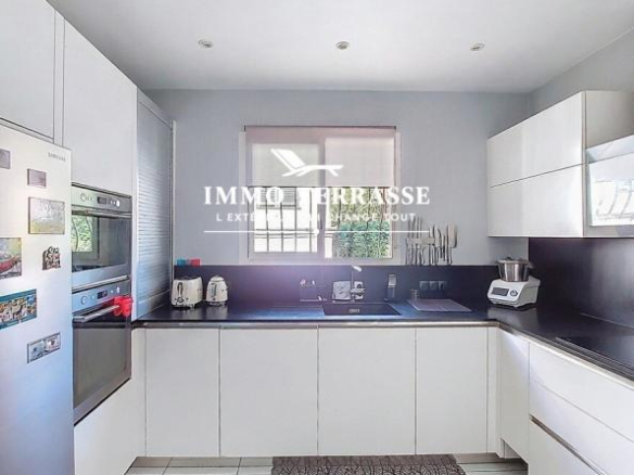Cuisine moderne d'une maison à Nice, avec des meubles blancs et des appareils électroménagers en inox.