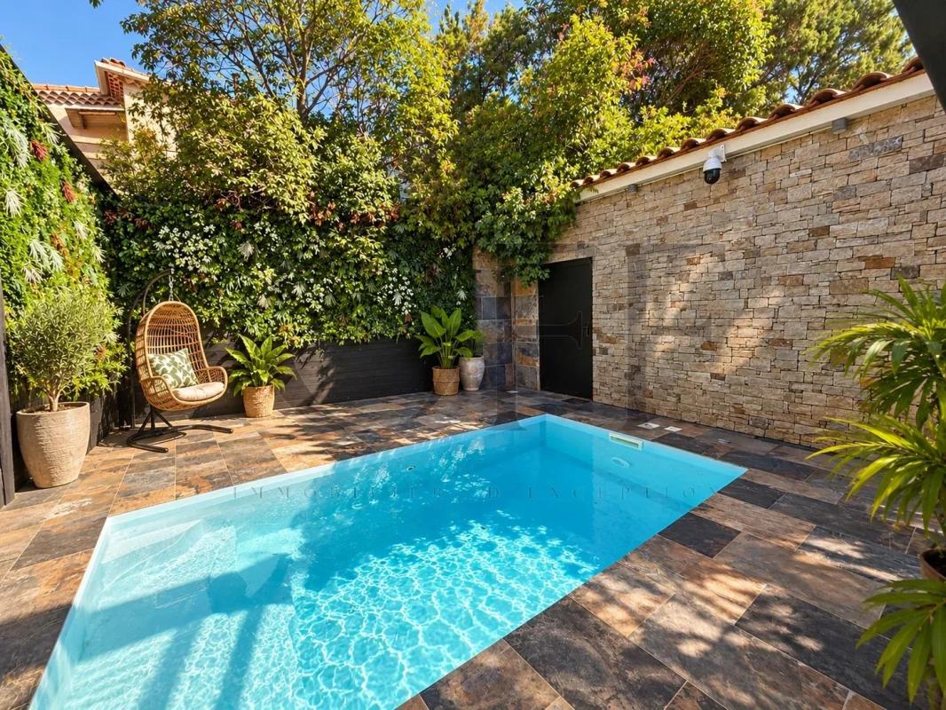 Villa de plain-pied avec piscine à Marseille 13e Piscine de villa de plain-pied à Marseille 13e, entourée de végétation et de murs en pierre.