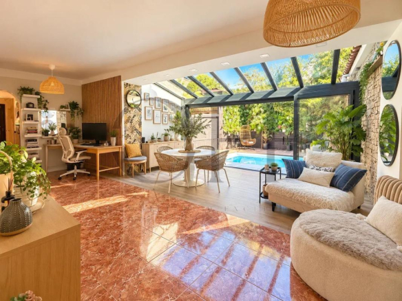 Intérieur d'une villa de plain-pied avec salon lumineux, piscine visible à l'extérieur.