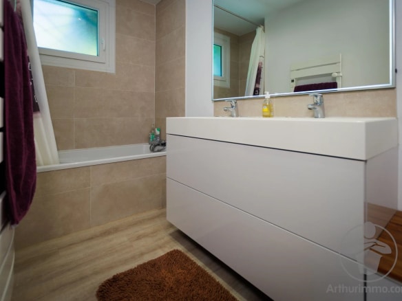Salle de bain moderne avec baignoire, lavabo et miroir, dans une maison à Sanguinet.
