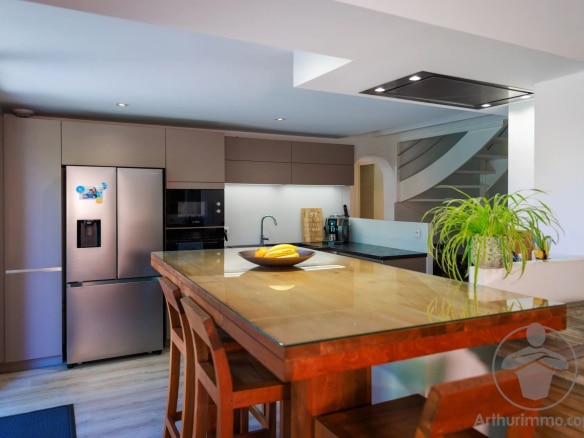 Cuisine moderne avec un bar en bois et des appareils électroménagers en inox.