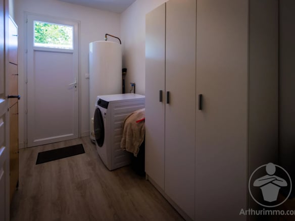 Intérieur d'une maison avec une buanderie, machine à laver et rangements.